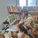 Tygryski w Bibliotece- dzieci oglądają książkę pod powiększalnikiem 