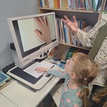 Tygryski w Bibliotece- dziecko ogląda rękę pod powiększalnikiem