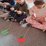 Dzień Jabłka - dzieci nawijają sznurki z jabłkiem na patyk