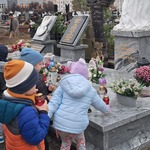 Zbliża się Dzień Wszystkich Świętych - dzieci ustawiają znicze na grobie