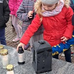 Zbliża się Dzień Wszystkich Świętych - dziecko stawia znicz na grobie
