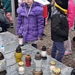 Zbliża się Dzień Wszystkich Świętych - dziecko stawia znicz na grobie