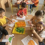 Dzień Dyni w grupie Słoneczka- dzieci przy stoliku wykonują prace plastyczną