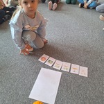 Dzień Dyni w grupie Tygryski- dziewczynka na dywanie ułożyła obrazkowy cykl rozwoju dyni
