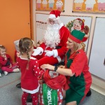 Mikołajki w przedszkolu - dziewczynka odbiera prezent od Mikołaja