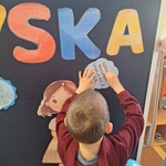 Niebieskie Igrzyska- dziecko przypina informacje nt. osób w spektrum autyzmu