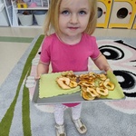 Dzień jabłka w naszym przedszkolu- dziecko z taca suszonych jabłek 
