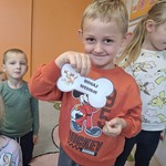 Dzień kundelka - zabawy ruchowe z kostka- chłopiec trzyma szablon kości z zadaniem do wykonania 