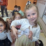 Dzień kundelka - zabawy ruchowe z kostka- dziewczynka trzyma szablon kości z zadaniem do wykonania 